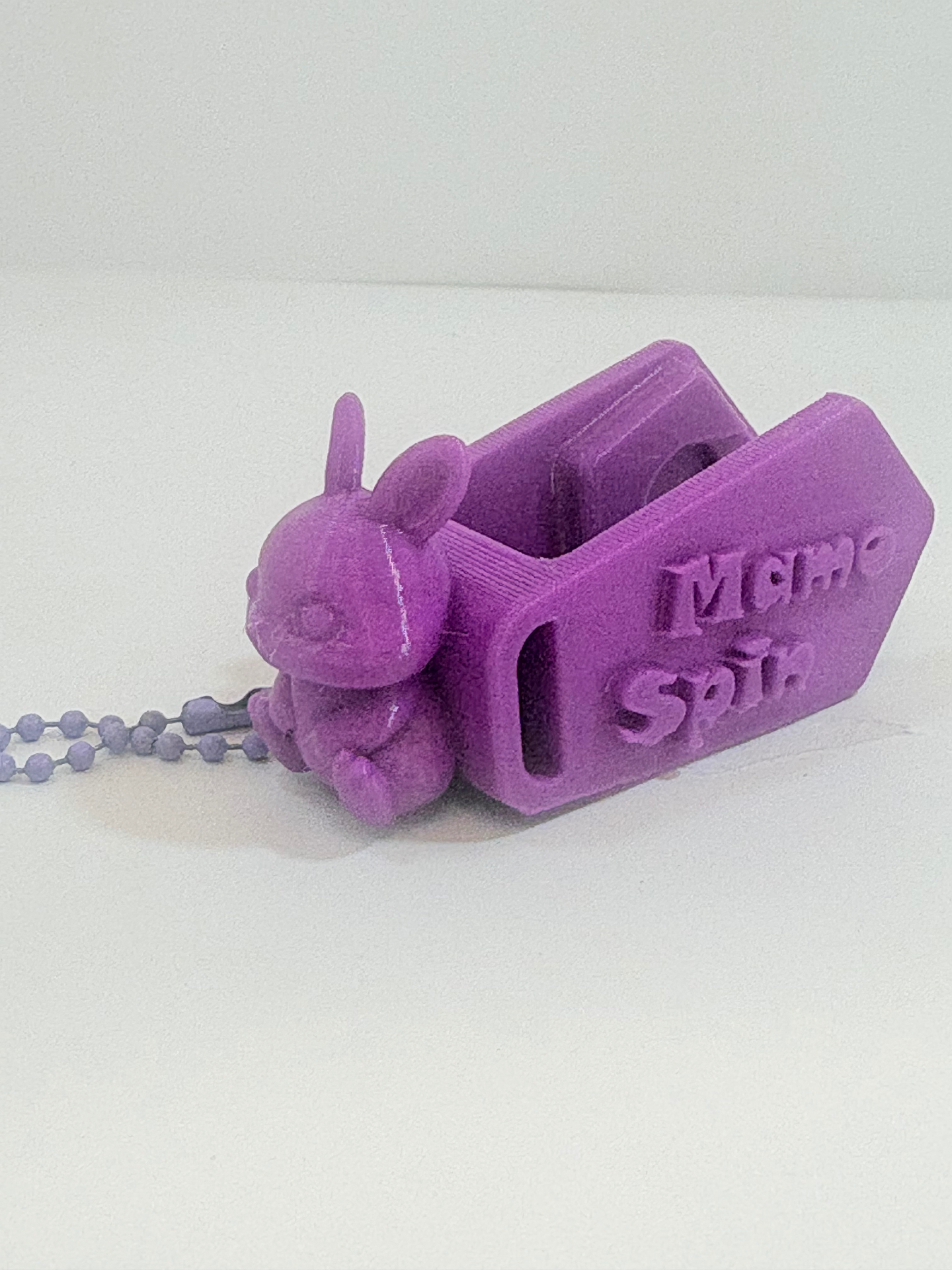 MamoSpin Pufli — coelho roxo de lado, mostrando o prendedor Mamo Spin