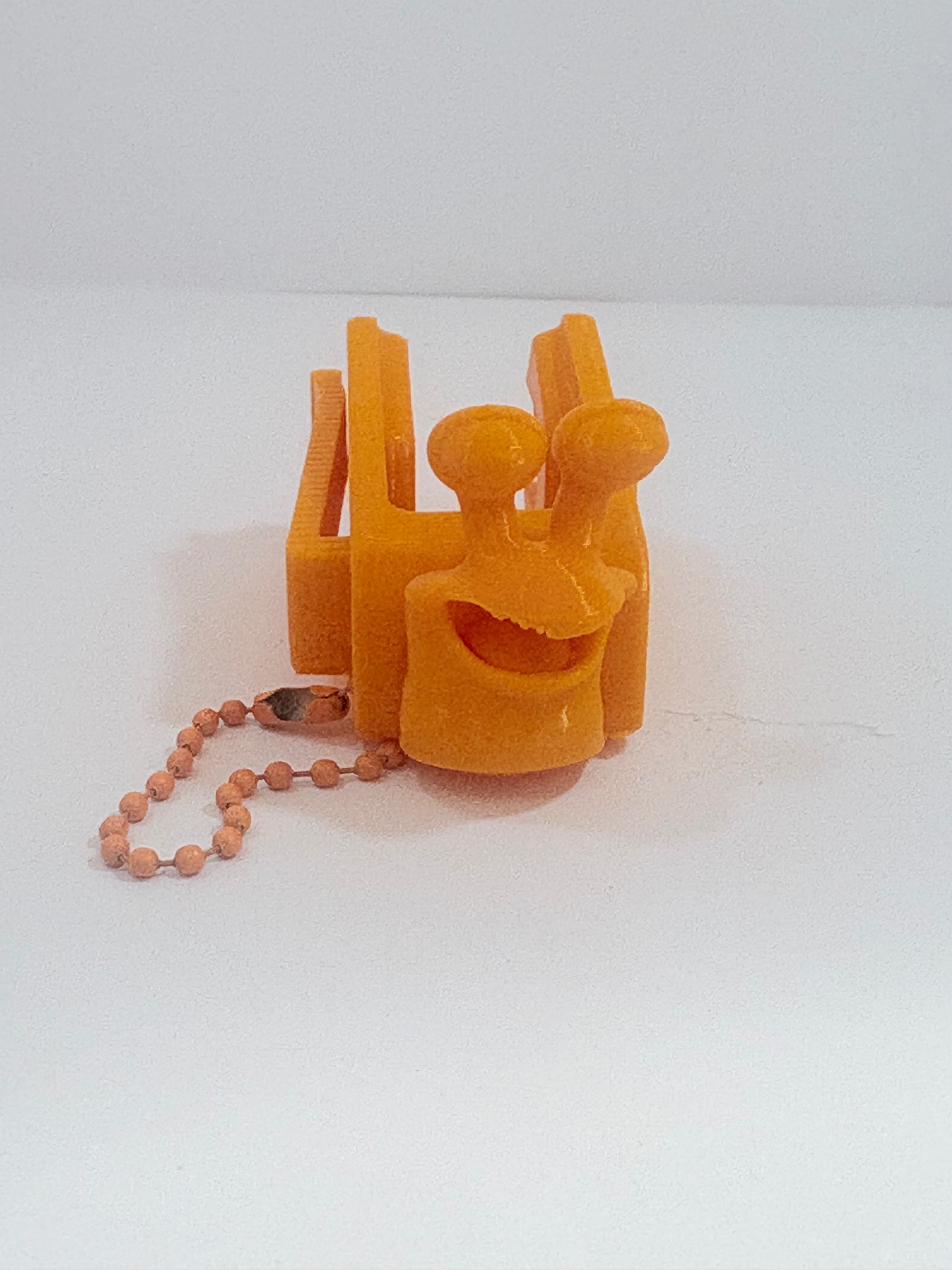 MamoSpin Lulko — caracol laranja de frente, no prendedor com corrente