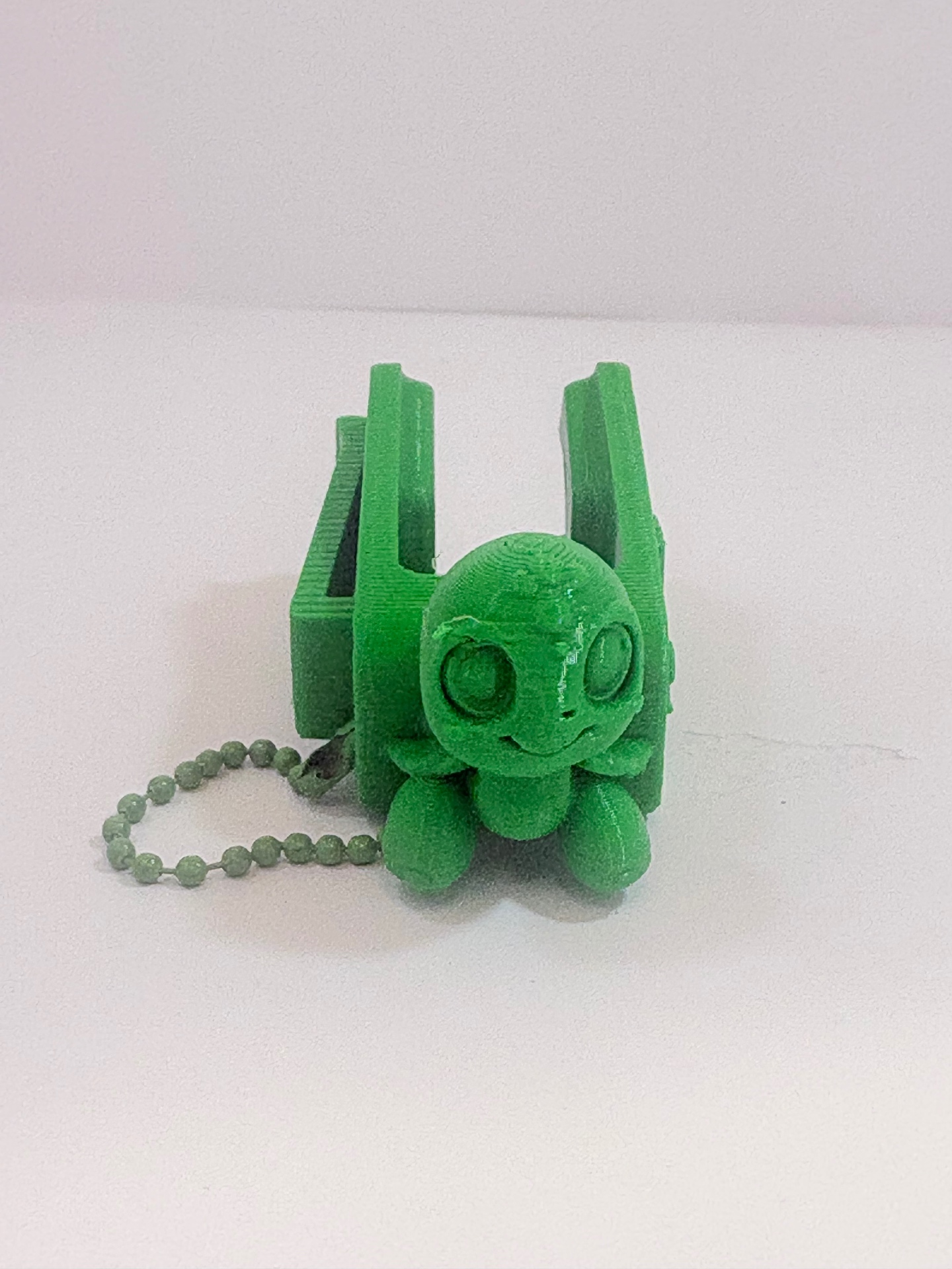 MamoSpin Kelpi — tartaruga verde de frente, no prendedor com corrente